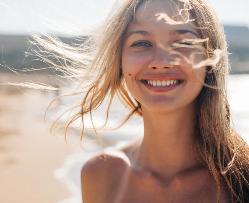 Woman at the beach with hair blowing across her face